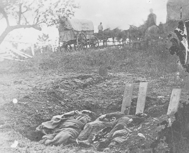 Our knowledge of initial burial practices on the battlefield has been pieced together from a variety of sources. Most importantly, a few early photographs— many of them now well-known iconic images of American history—capture steps in the process of temporary burials. Among these images, Alexander Gardner's of July 5,1863 mark the earliest and most poignant. This photo at the Rose Farm is the only one to demonstrate the burial practices of the initial internment on the battlefield. Mass, temporary graves were employed directly on the field so that corpses could be more rapidly protected by at least a few inches of earth. Planks were often used to identify those who could be named, but many went nameless. Most of these initial burials were exhumed and reburied within months in a permanent resting spot such as the Soldiers' National Cemetery. Source: Gettysburg National Military Park Archives.