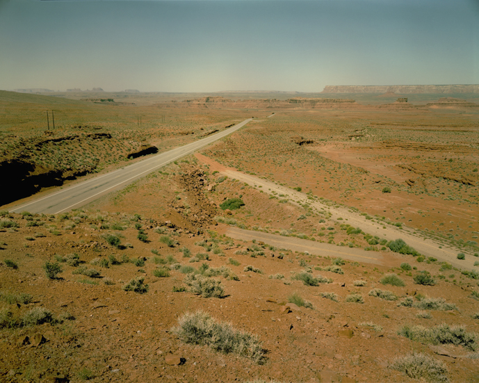 June 18, 1983. Contemporary U.S. 163 with two highway artifacts from previous versions of the highway. This view looks west toward Mexican Hat, Utah, which is a few miles away. When I revisited this spot in 2013, the two older highway fragments had completely disappeared with no traces visible. They were, literally, “marks on the land,” unintentional earth works, that proved to be ephemeral.