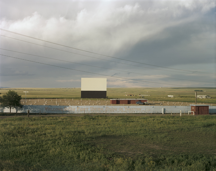 July 12, 1982. Las Vegas, New Mexico, is famously located where the Great Plains run up against the Rocky Mountains. The Fort Union Drive-in Movie Theater is located on the eastern edge of town near the old Santa Fe Trail, and this view looks east, past the big, white rectangle toward the High Plains prairie. The Fort Union is one of two active drive-in movie theaters left in the state of New Mexico and was still open when I went through in the summer of 2016.