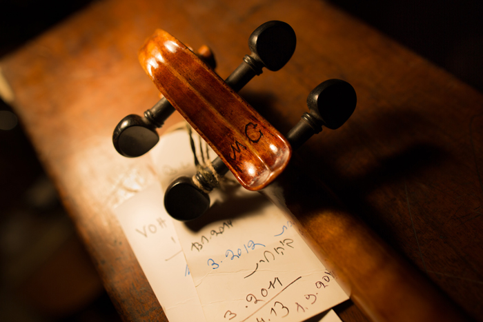 A carving of the letters M.C. on the back of a &lt;i&gt;Violin of Hope&lt;/i&gt; violin scroll. 