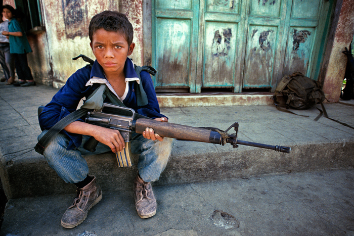 A young guerrilla fighter brandishes his M-16 rifle during a lull in fighting with government army forces, San Francisco Javier, Usulután Department, El Salvador, March 1989.