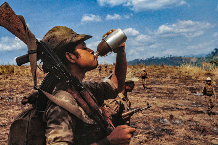 Soldiers of the elite Santos López Irregular Warfare Battalion of the Sandinista Popular Army cross a field while on an operation against the U.S.-backed Contra rebels, Jinotega Department, Nicaragua, June 1985.