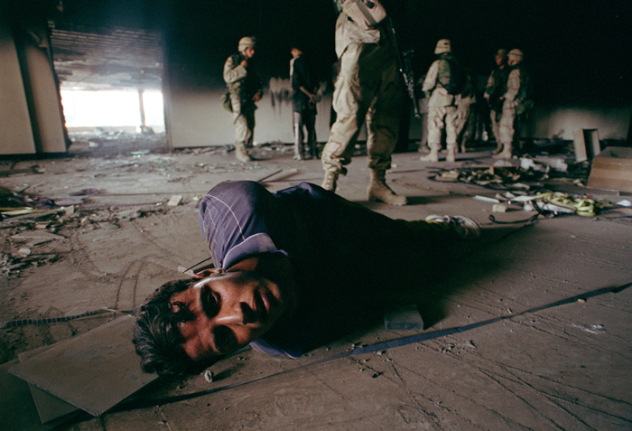 Suspected looters are detained by a U.S. Army patrol in Saddam Hussein’s former Ministry of Information building, which was heavily bombed in the early stages of the American-led invasion, Baghdad, Iraq, July 2003.